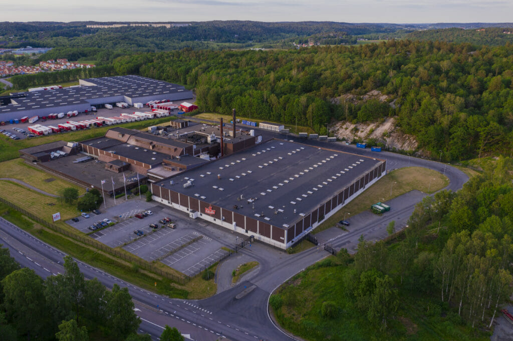 En drönarbild på Estrellas fabrik i Angered Göteborg under skymning. Ljuset är varm och något lila till färgen och horisonten syns